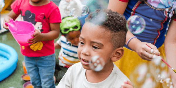 Menino sorrindo com bolhas de sabão em festa infantil